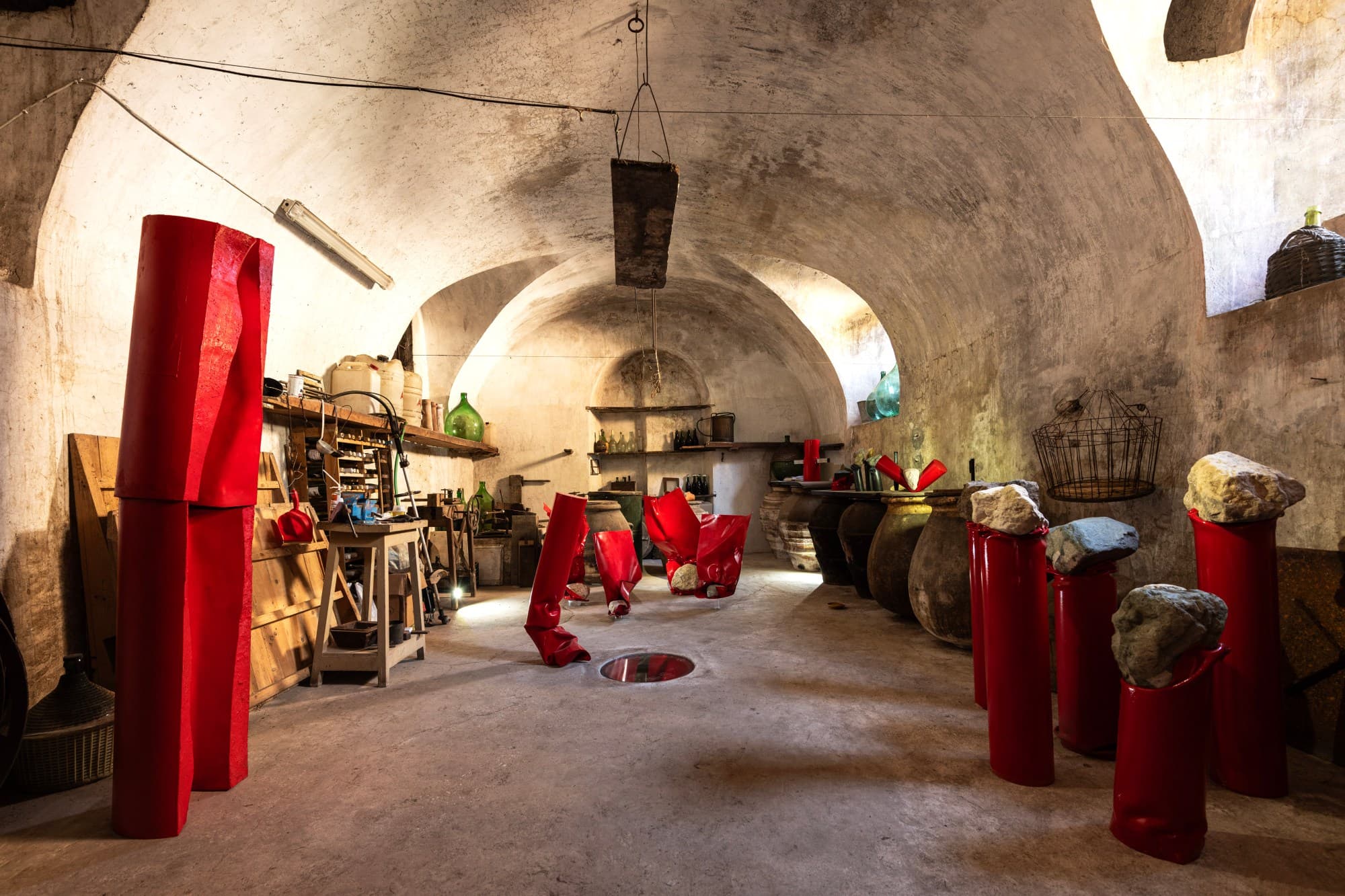 Lo studio di scultura di Studio Specus, ricavato nell'antica dispensa per l'olio: lo spazio voltato con le sculture in PVC rosso di Alberto Timossi e i lavori in pietra sui piedistalli.