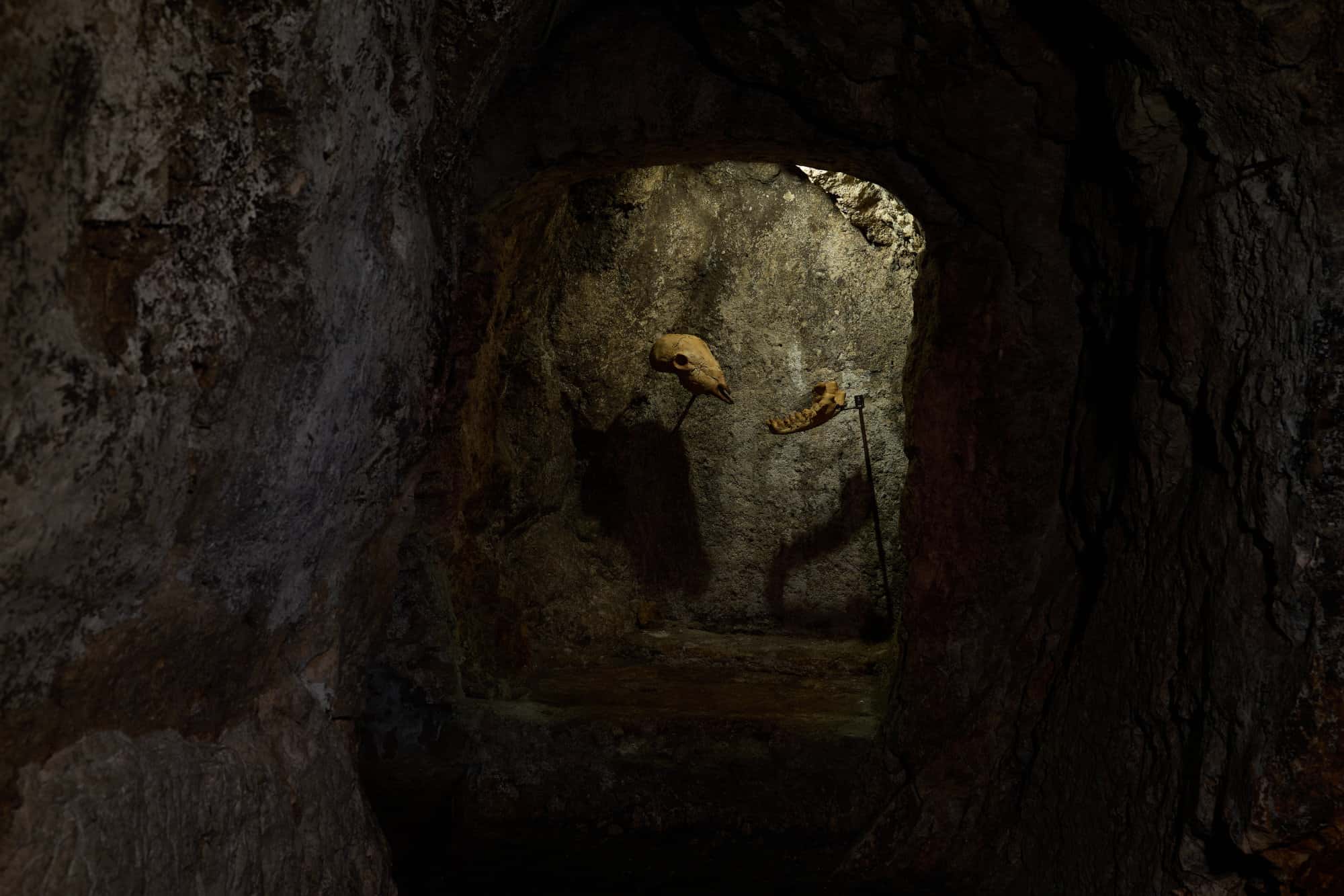 La grotta di Studio Specus durante ALCOVE 2026: in fondo al passaggio scavato nella roccia, le sculture di Francesco Petrone.