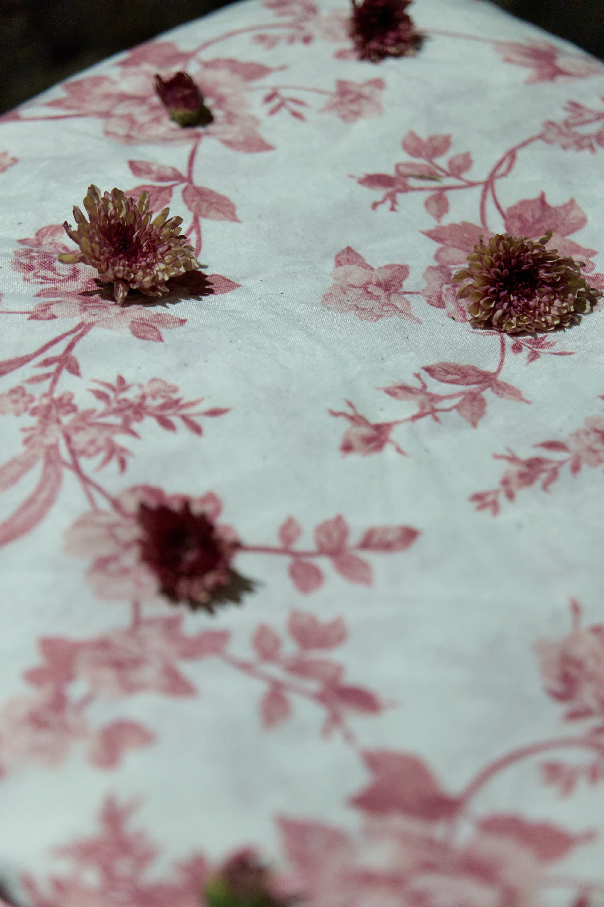 Dettaglio: fiori freschi che appassiscono sul motivo floreale rosso delle lenzuola.