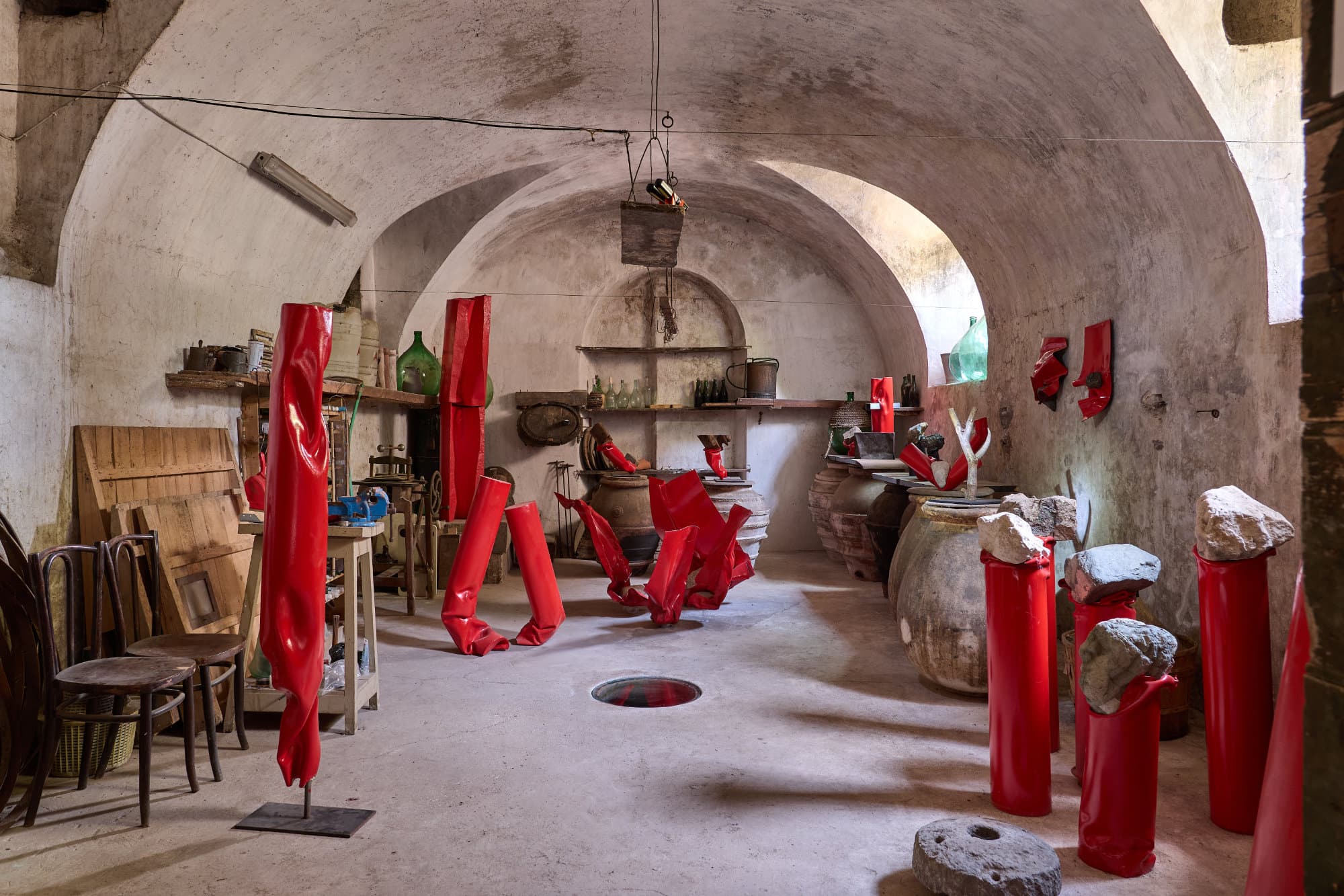 Lo studio di Alberto Timossi sotto le volte di Studio Specus, con le sculture rosse e i vecchi arredi della cantina.
