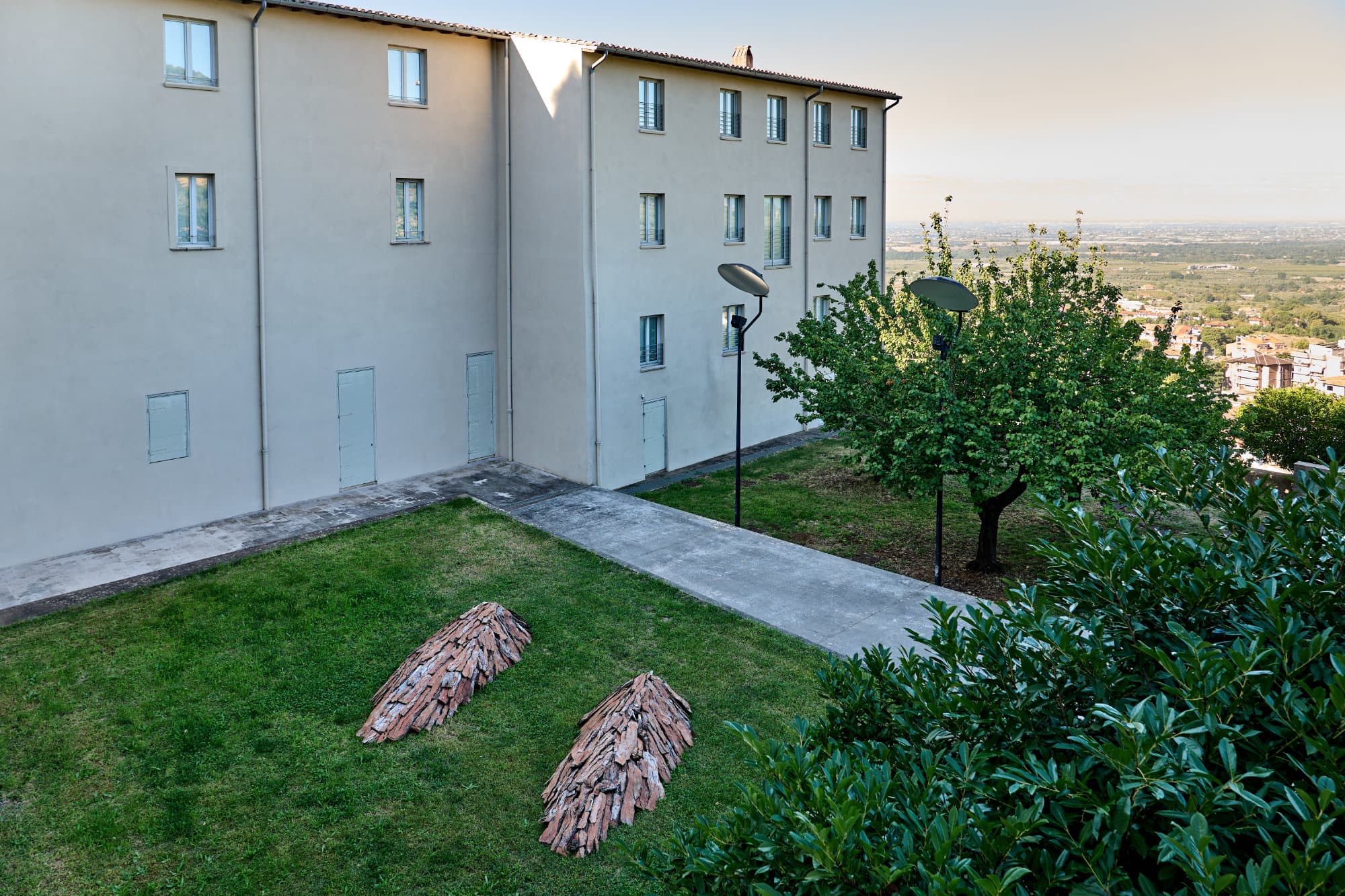 Il giardino del Museo con le due Tane di Pino Genovese sull'erba, aperto sul paesaggio.