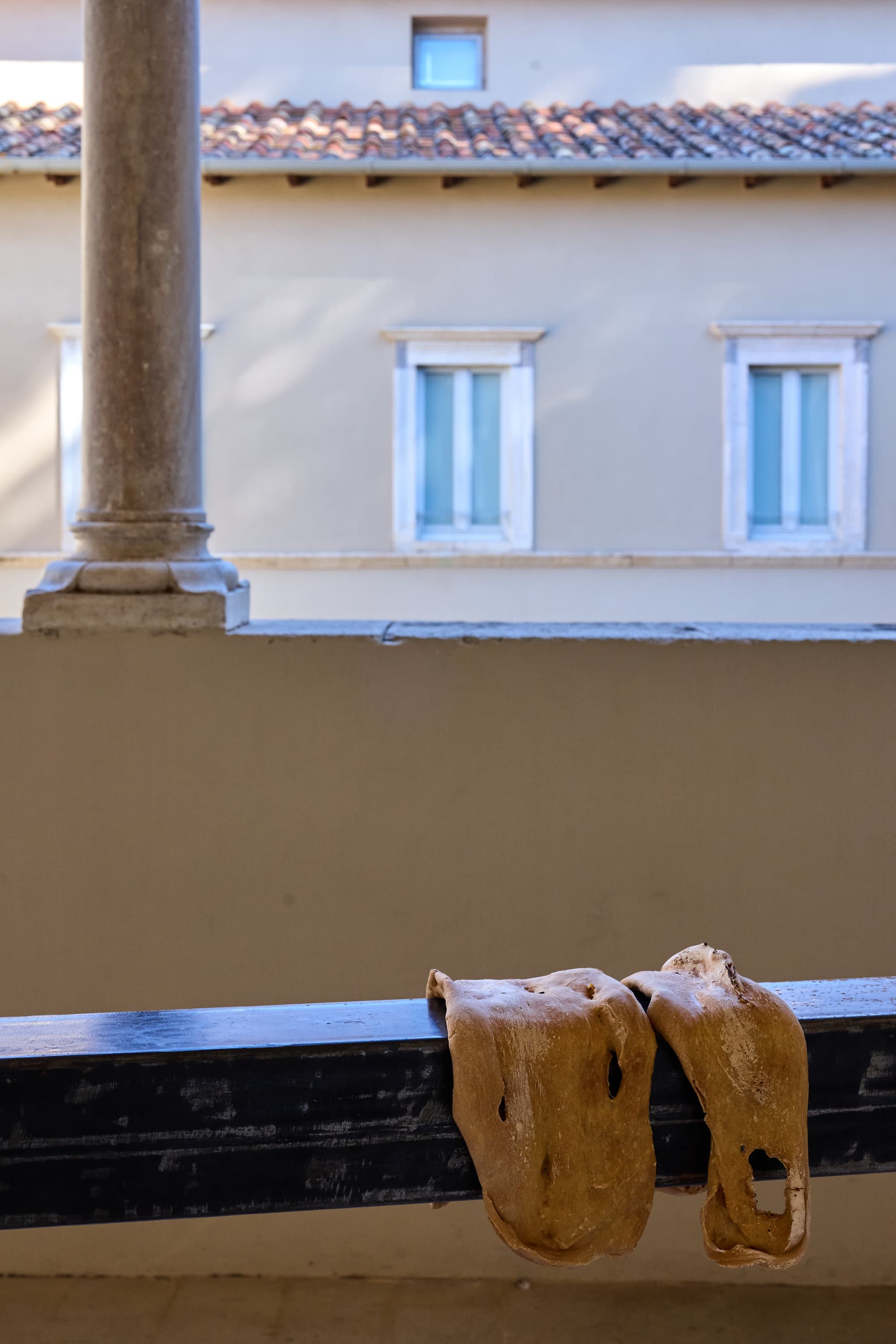 Dettaglio di L'ultima scena: lembi di pane posati sul palo di ferro, tra le colonne della Loggia.