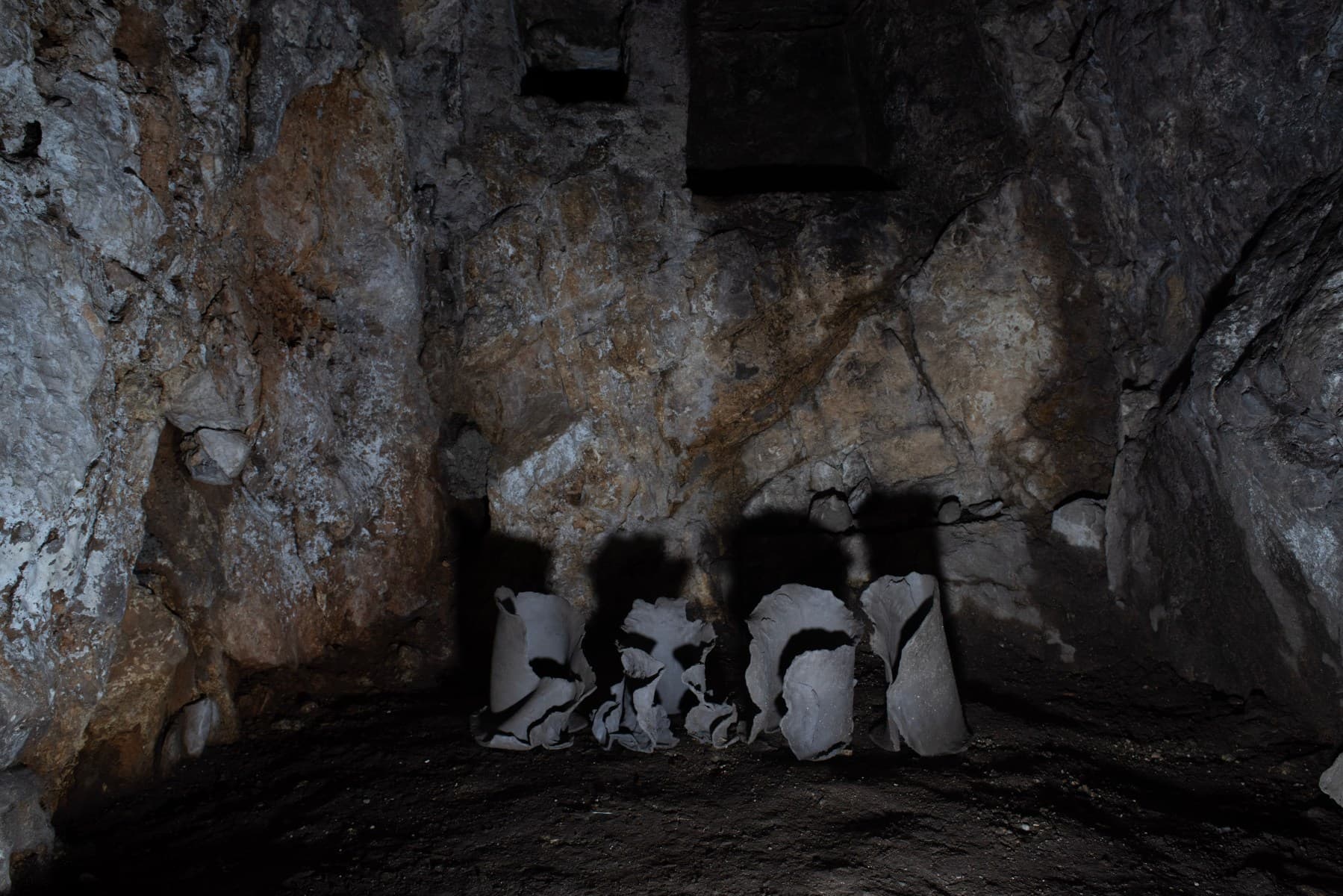Piccole sculture in ceramica refrattaria di Arianna De Nicola poggiate a terra nella grotta.