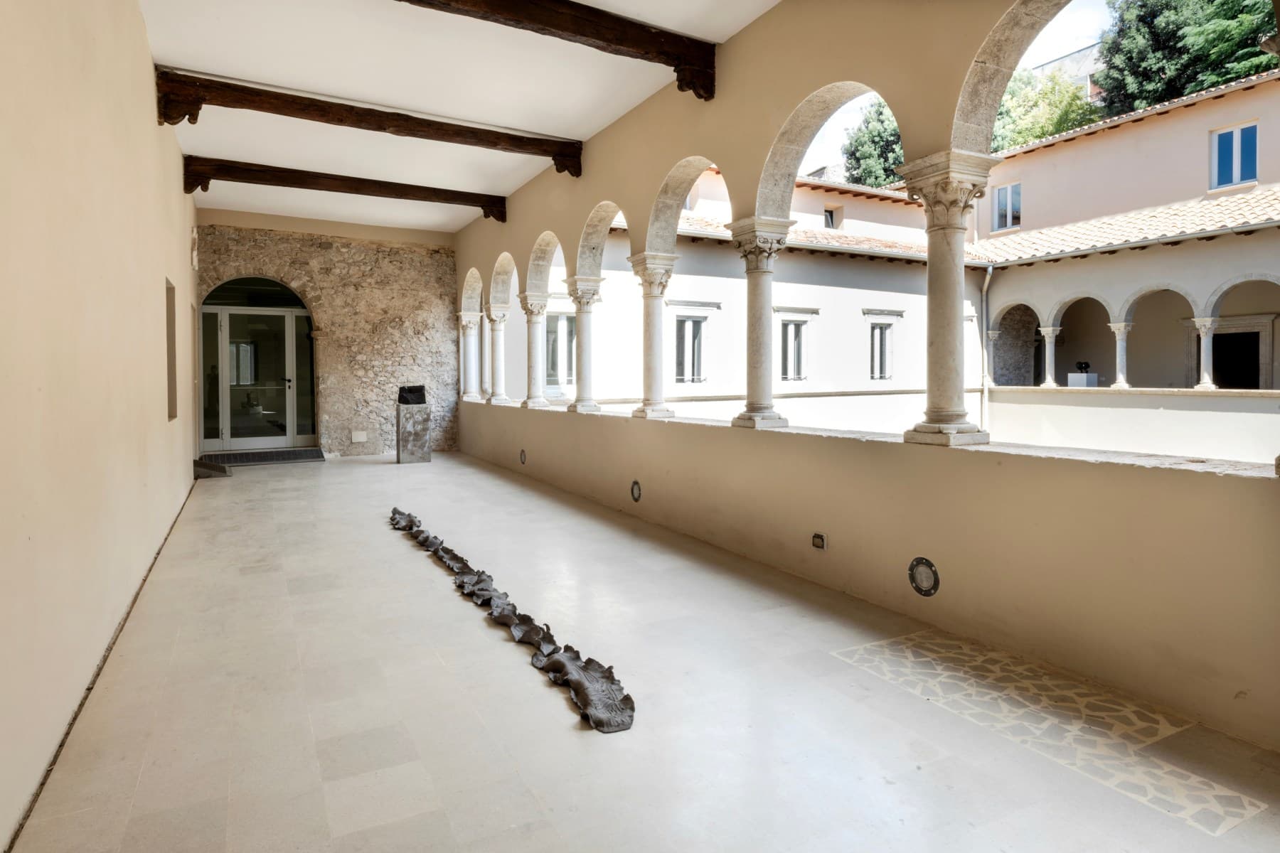 La linea del giardino di Arianna De Nicola si distende sul pavimento della loggia, accanto all'opera di Graziano Pompili.