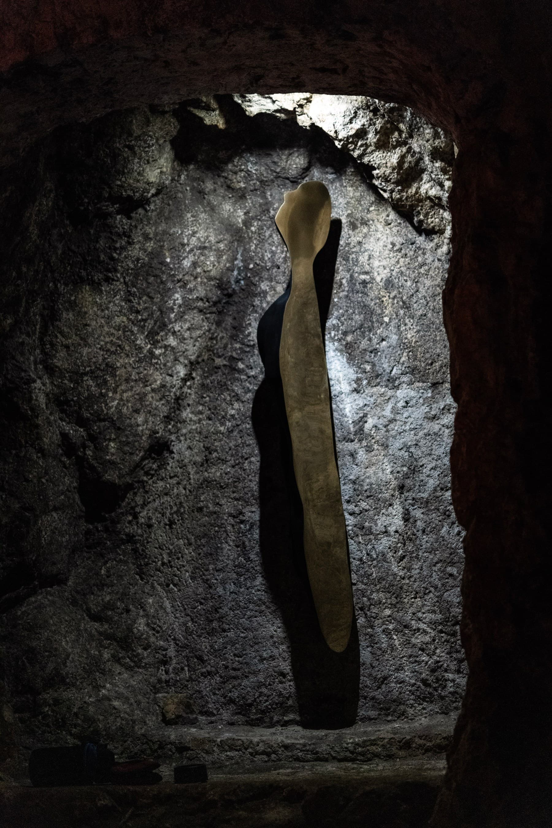 L'uomo-buio di Paolo Garau, metà nero metà specchiante, nella nicchia della grotta.