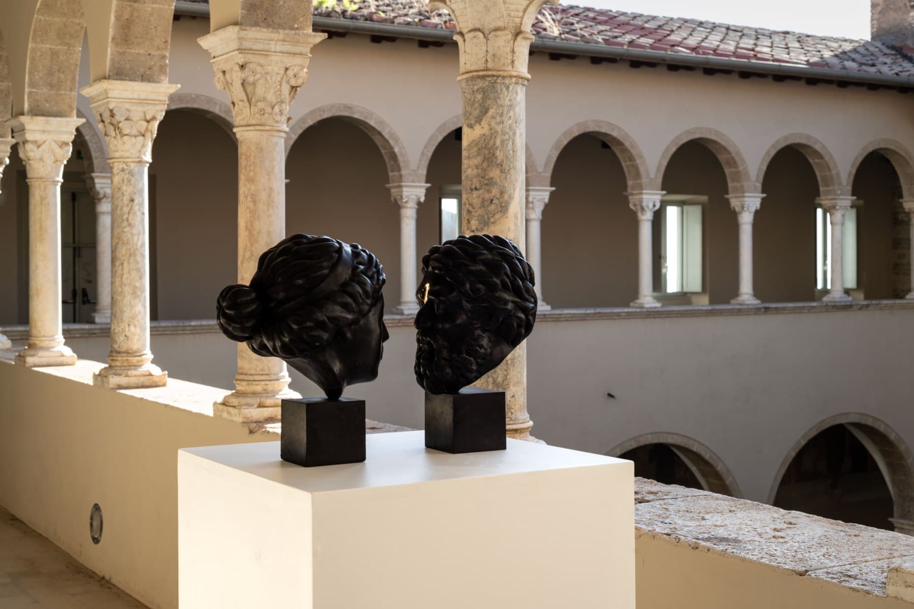 Due teste di Paolo Garau disposte l'una di fronte all'altra nella loggia del Museo.