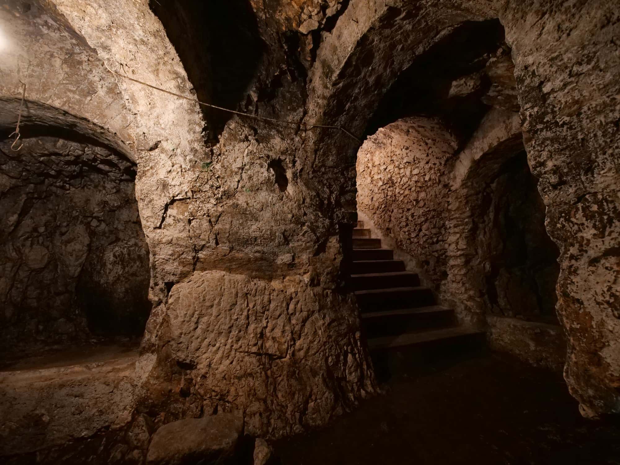 La grotta naturale di Studio Specus: archi in pietra e una scala scavata nella roccia, nel buio.
