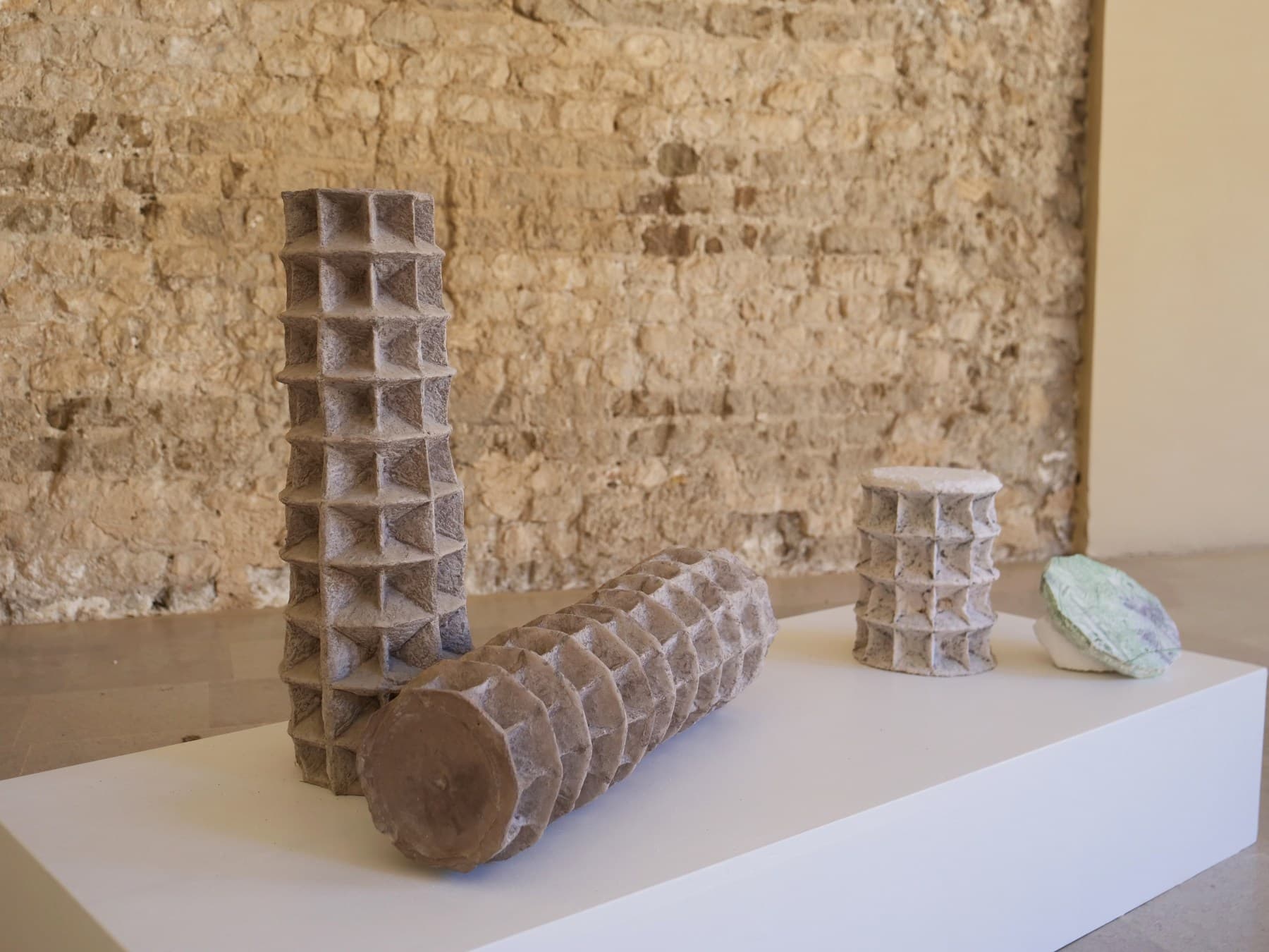 Le sculture in cemento di Meletios Meletiou, dal pattern a bugnato, contro la parete in pietra della loggia.